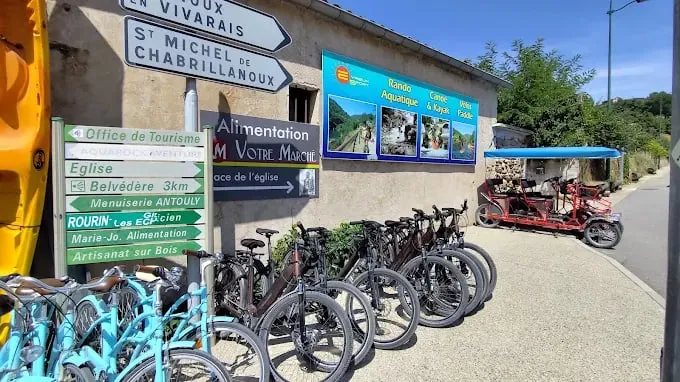 Base Eyrieux Sport aux Ollières-sur-Eyrieux — vélos alignés devant la boutique, rosalie et kayak, au départ de la Dolce Via